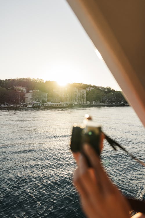 A person taking a photo of the sun from a boat