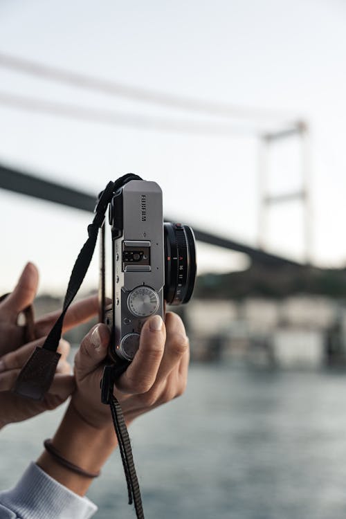 A person holding a camera over a body of water