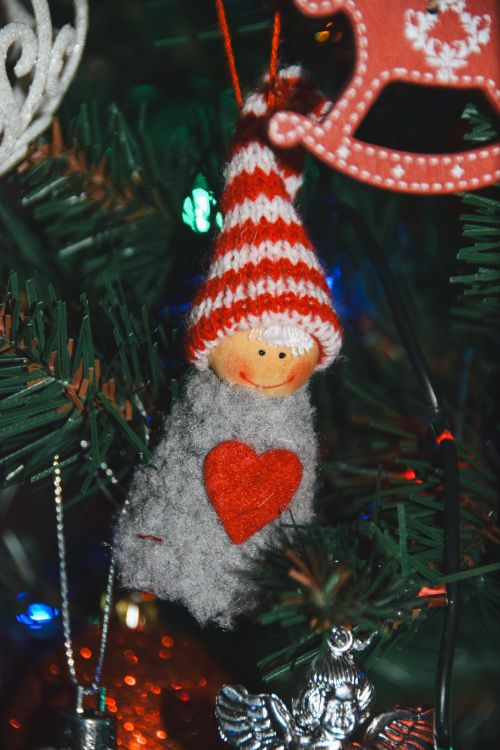 Free Close-up of a whimsical Christmas tree ornament with a red heart and striped hat. Stock Photo