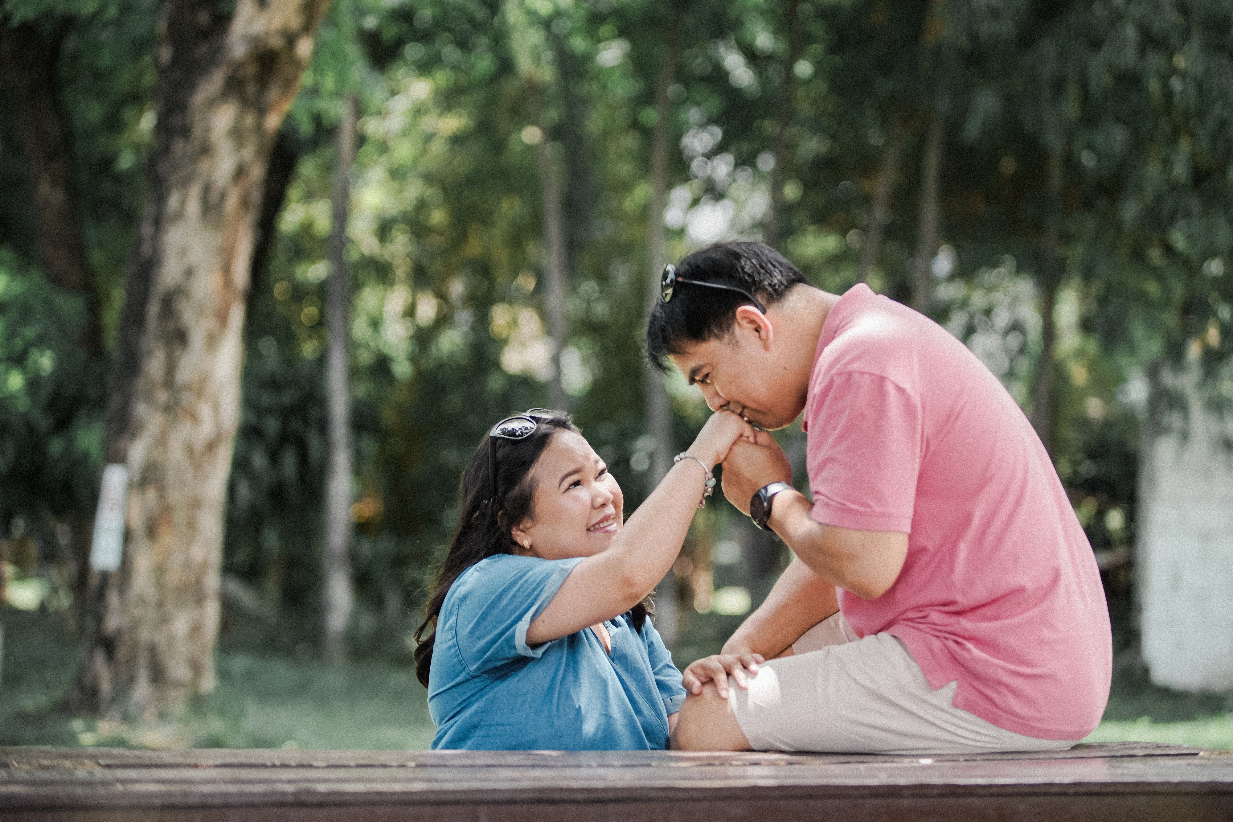 Happy couple expressing love in a sunny park setting, capturing a joyful moment of connection.