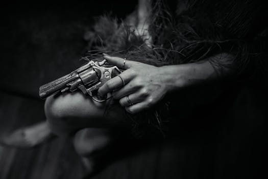 Moody black and white close-up of a hand holding a revolver, in noir style.