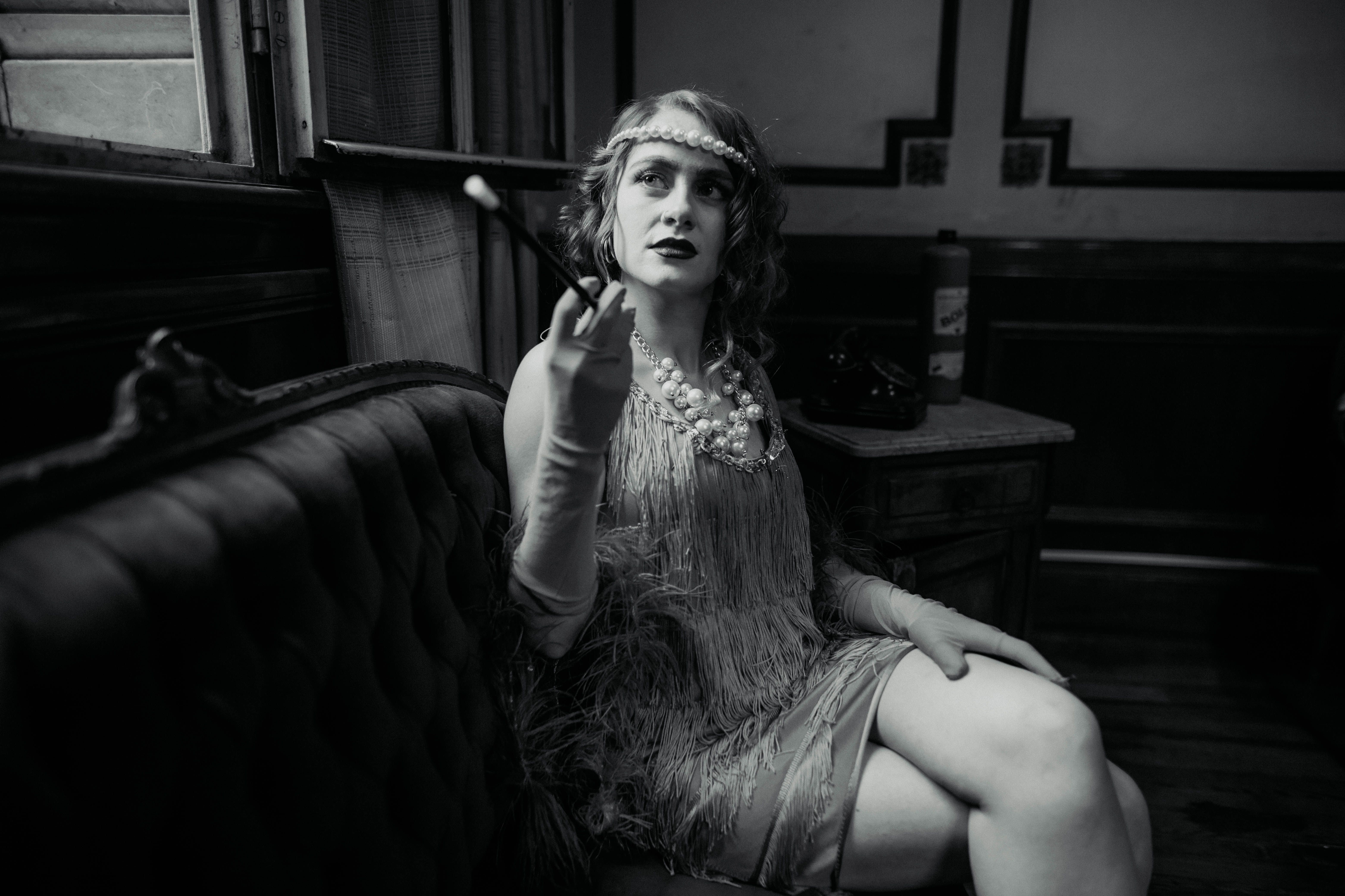 A woman sitting on a couch smoking a cigarette · Free Stock Photo