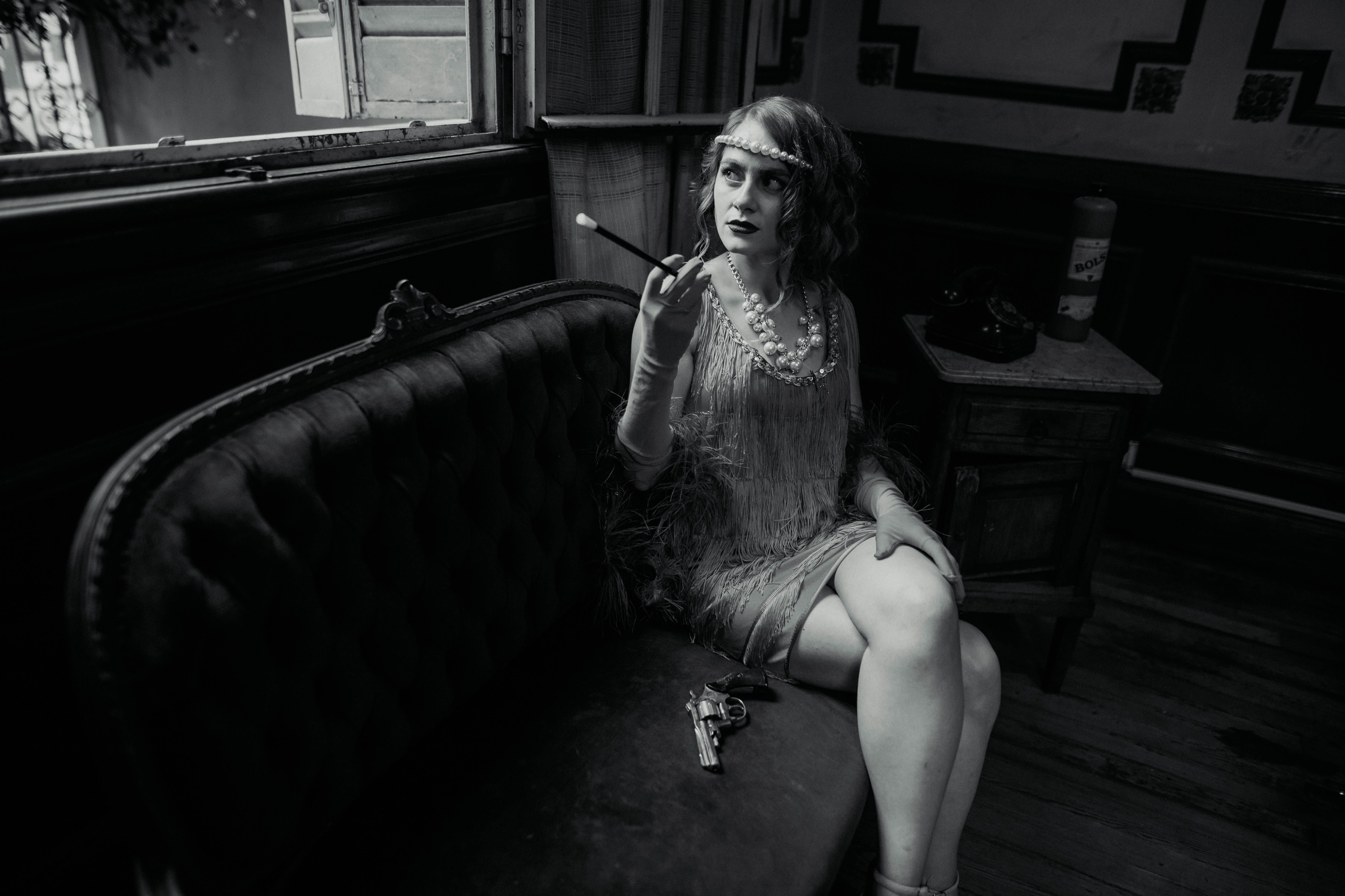 A woman sitting on a couch smoking a cigarette · Free Stock Photo