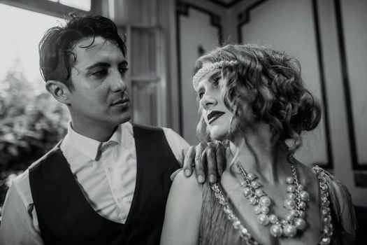 A stylish couple in 1920s attire gazing lovingly at each other in a vintage Buenos Aires setting.
