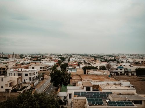 Free Aerial cityscape showing residential buildings and solar panels under a cloudy sky. Stock Photo