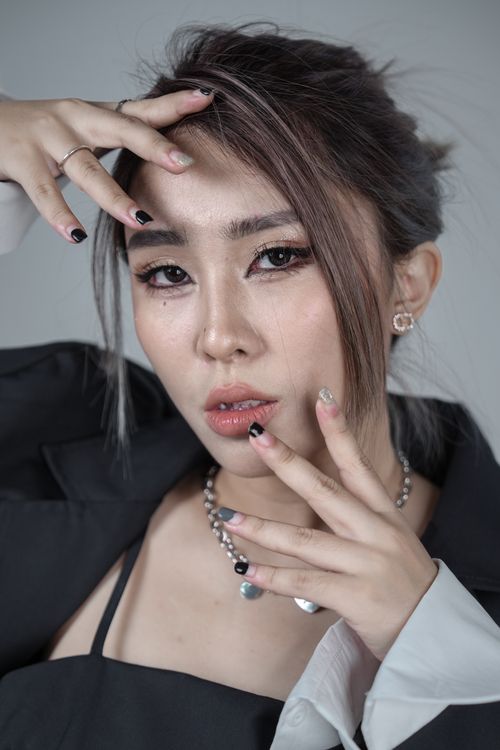 Free A sophisticated Asian woman posing with elegance in a studio setting on a gray background. Stock Photo