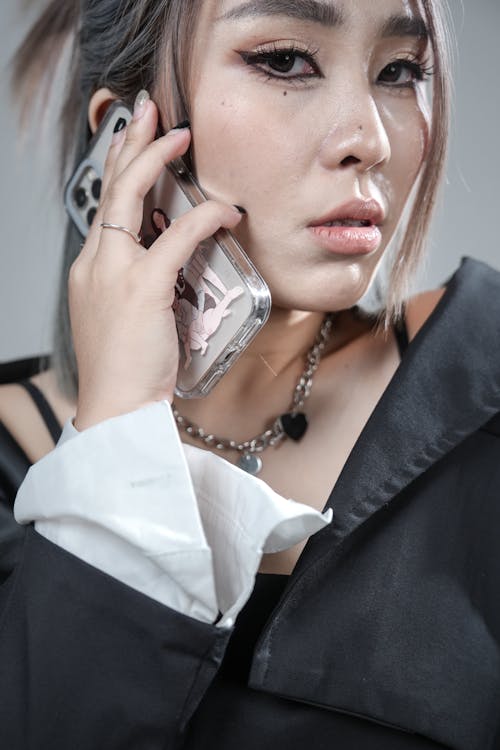 A woman with a black shirt and necklace talking on a cell phone