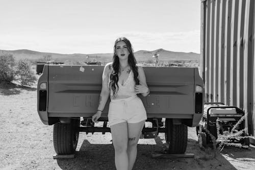 A woman in shorts standing next to a truck