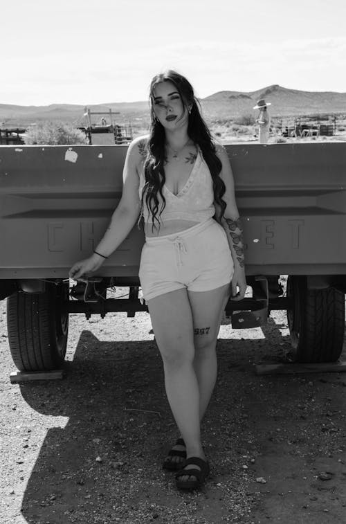A woman in shorts and a tank top standing next to a truck