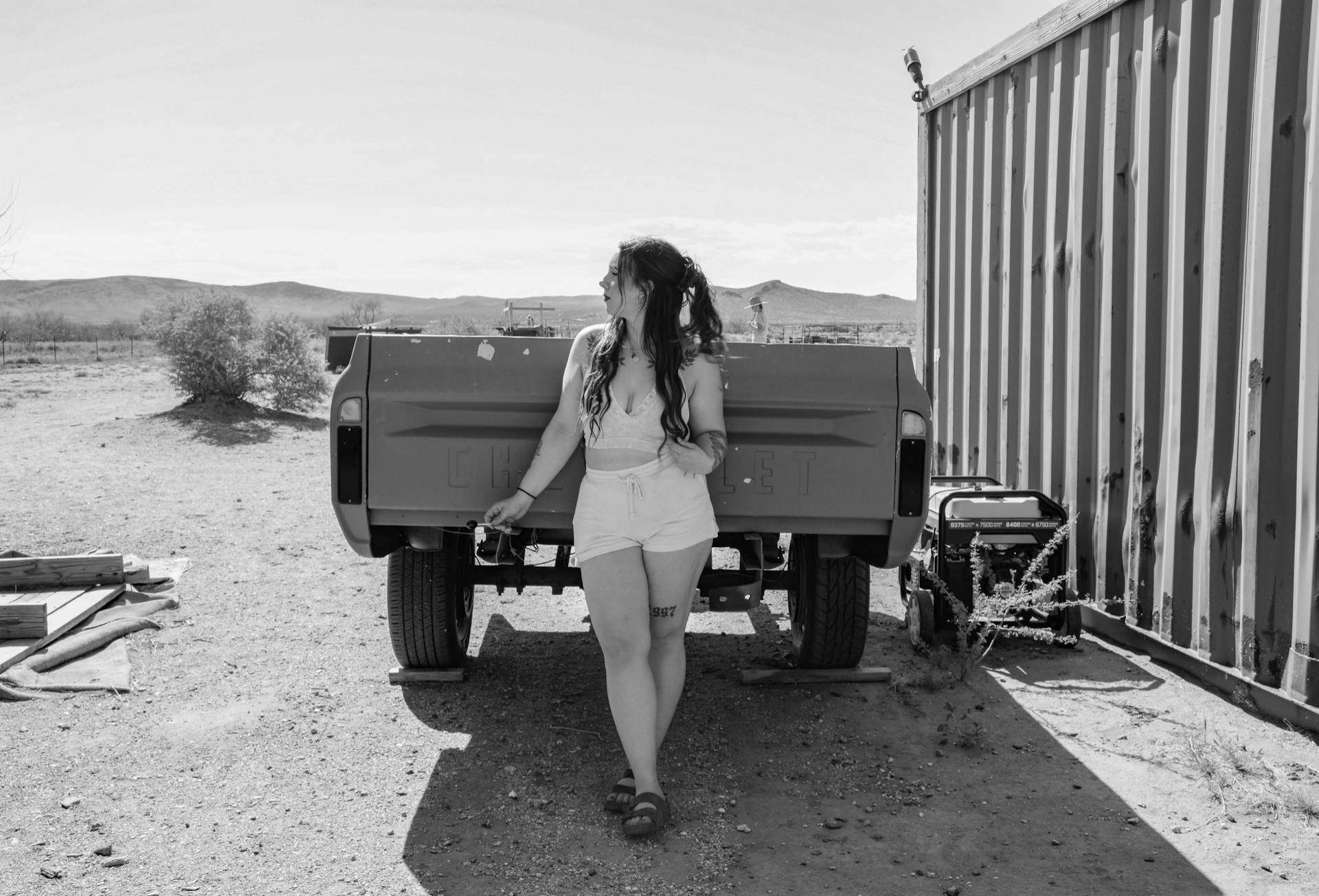 Black and white image of a woman by a trailer in Dolan Springs, AZ.