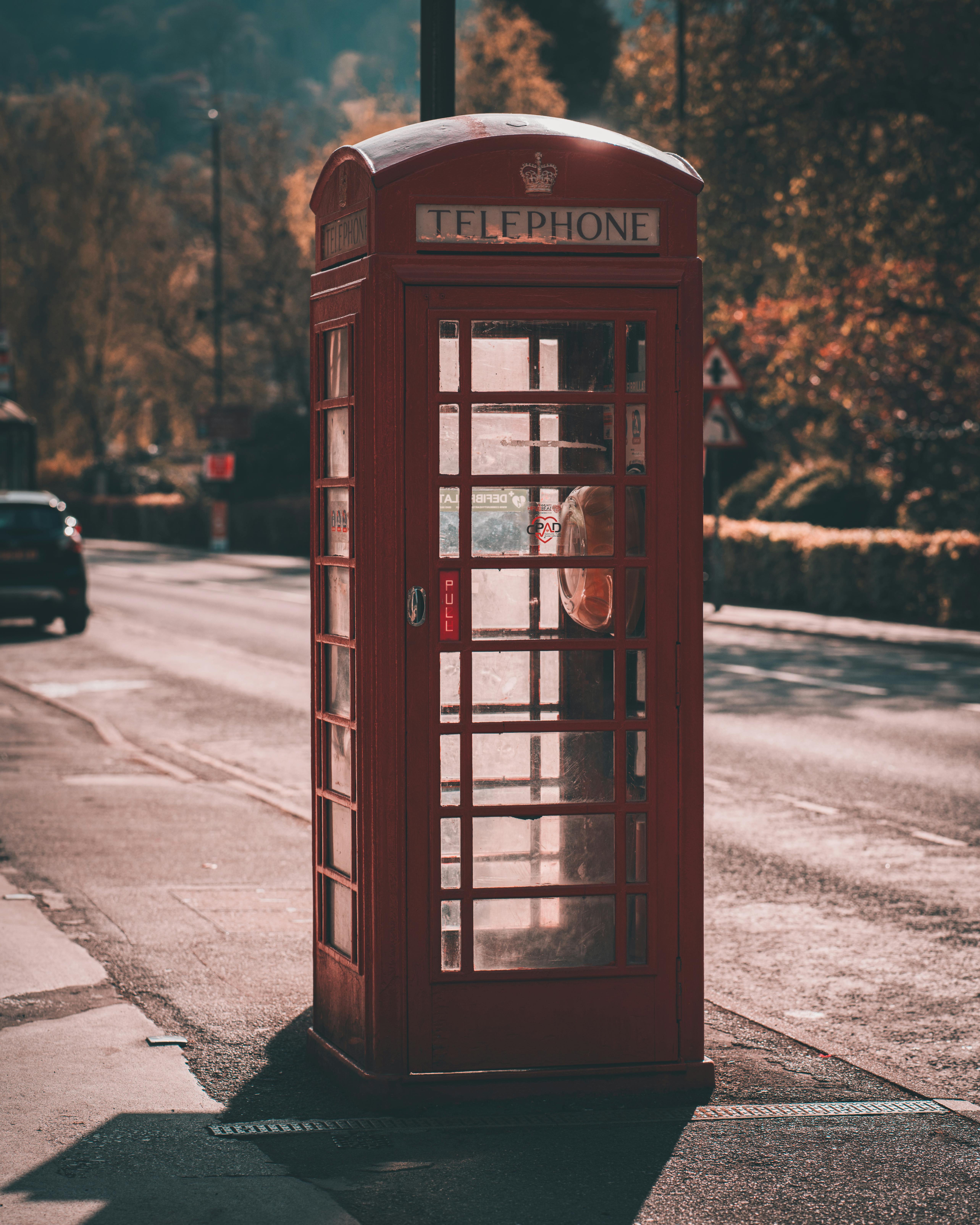 Classic red telephone booth on a quiet urban street, embodying nostalgic retro charm.