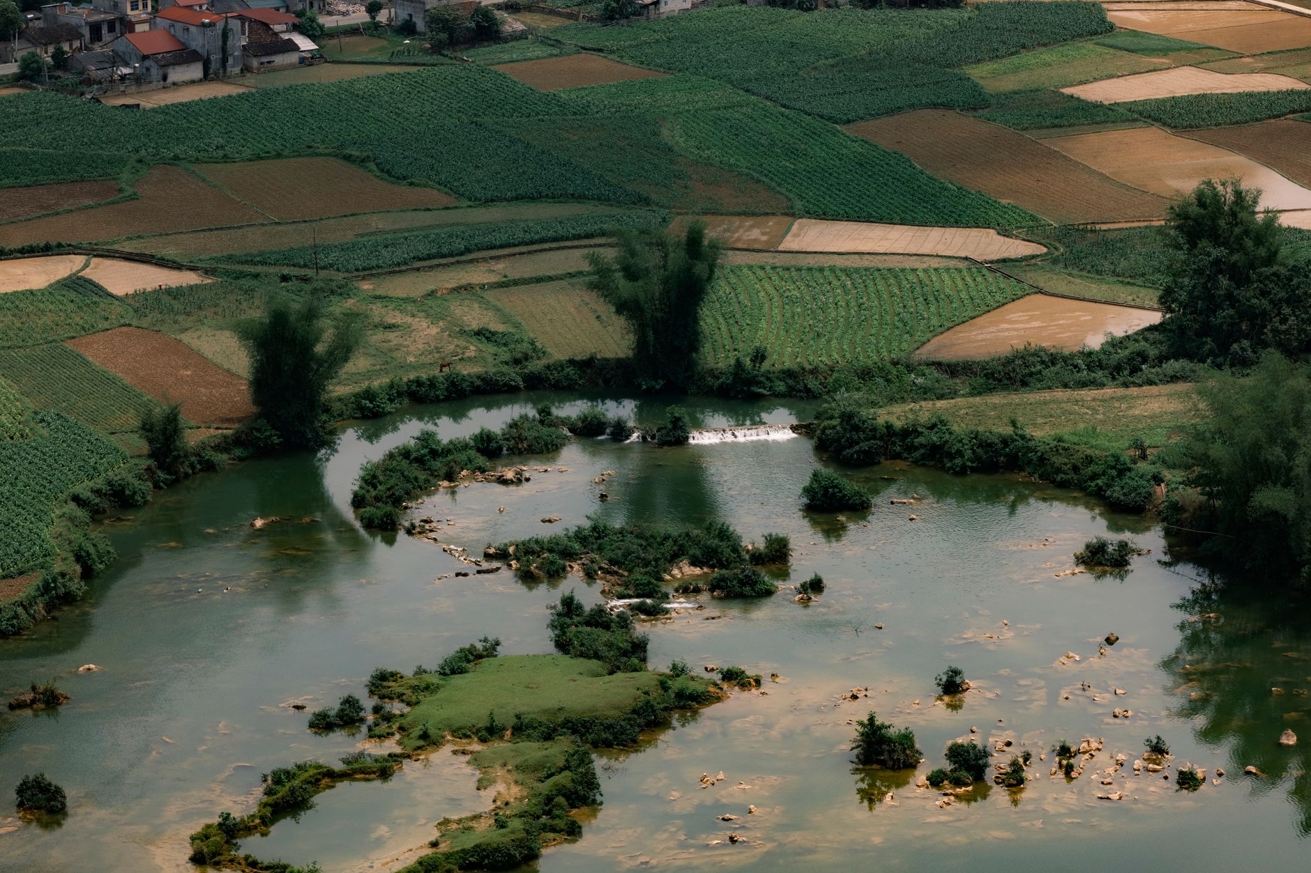Aerial landscape of lush fields and river in Cao Bang, Vietnam, showcasing rural beauty.