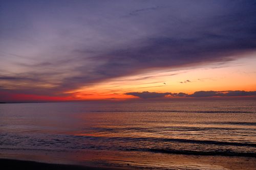 Free Beautiful sunset over the ocean with vivid colors and serene waves. Stock Photo