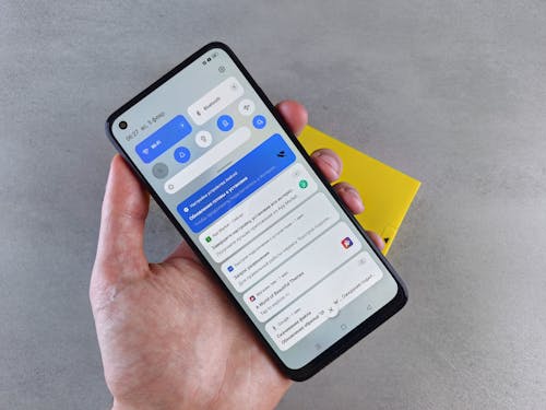 Free A close-up of a hand holding a smartphone displaying multiple notifications, highlighting modern technology. Stock Photo