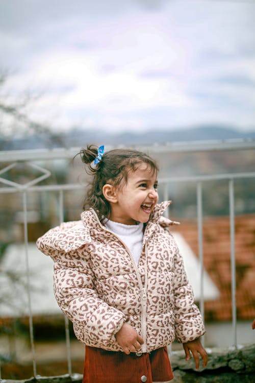 A little girl is smiling while standing on a balcony