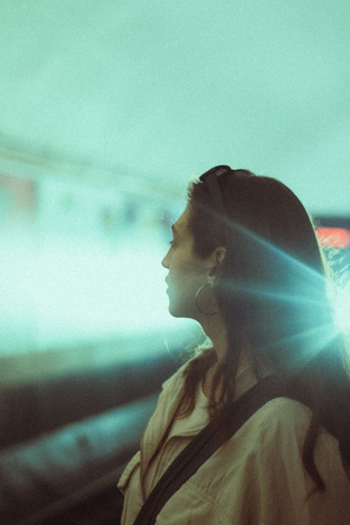 Free Silhouette of a brunette woman standing in an urban subway station tunnel with bright headlight flare. Stock Photo