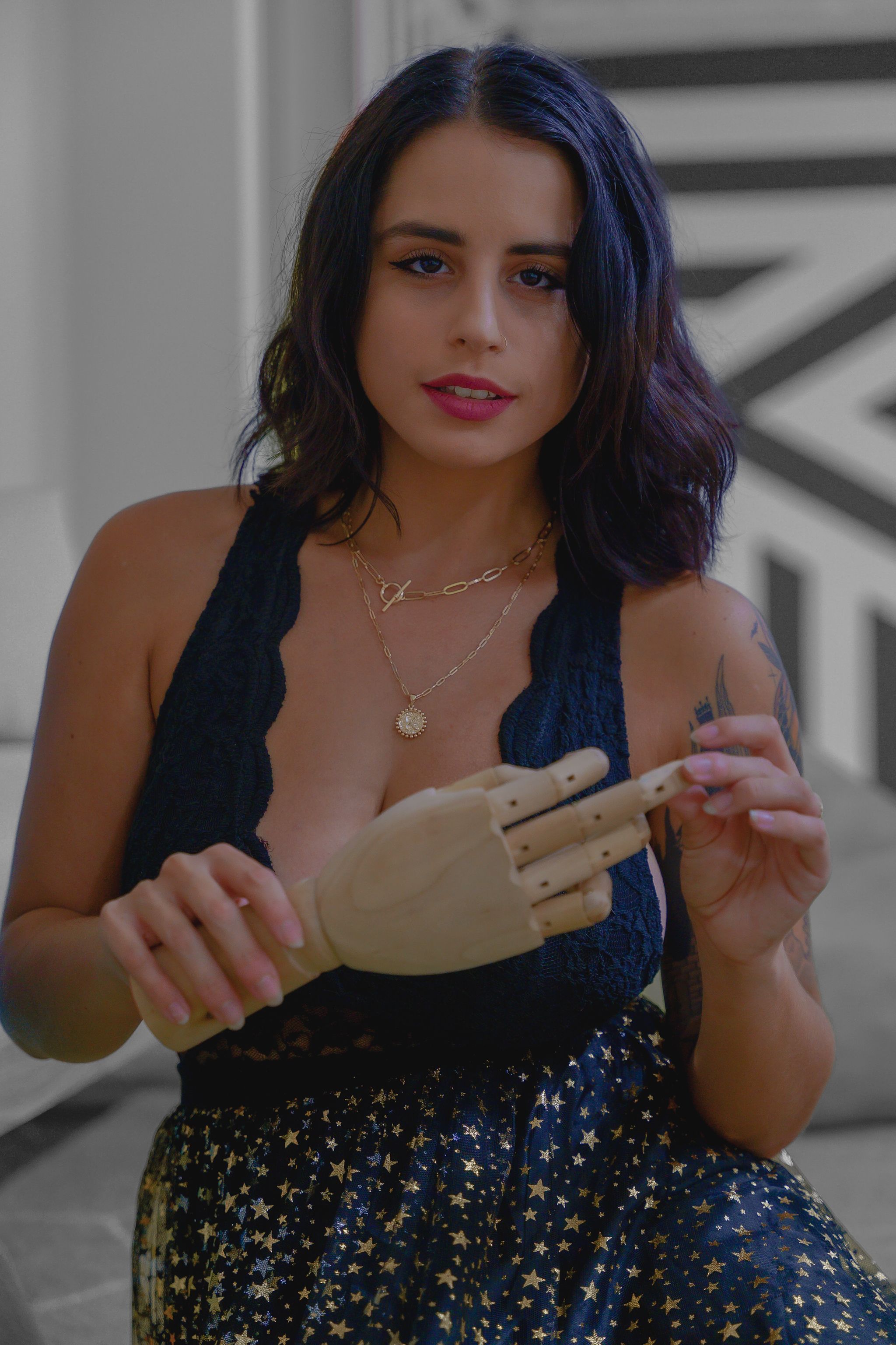 Stylish woman in a starry skirt holding a prosthetic hand indoors.