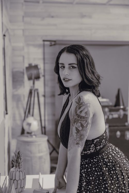 Free Monochrome portrait of a woman with tattoos, wearing a stylish dress indoors. Stock Photo