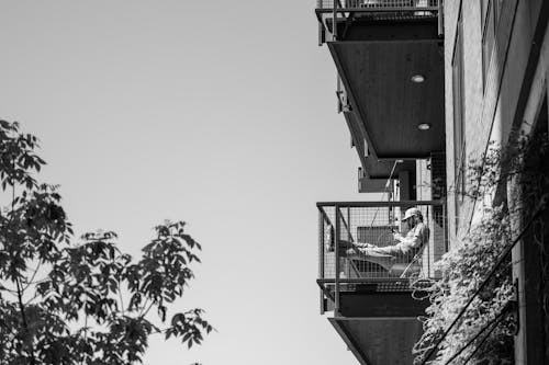 Black and white photo of a balcony with a person sitting on it