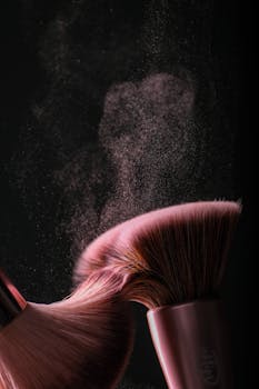 Close-up shot of makeup brushes with powder scattering against a dark background capturing motion and elegance.