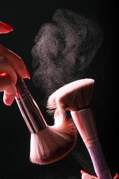 Dynamic studio shot of makeup brushes creating a powder burst against a dark background.