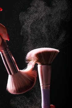 Close-up of makeup brushes with powder cloud against a dark studio background, showcasing movement.