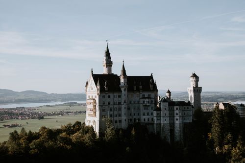 Free Dramatic view of Neuschwanstein Castle surrounded by lush greenery, set in the Bavarian landscape. Stock Photo