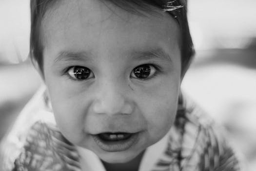 Engaging black and white close-up portrait of a child with expressive eyes.