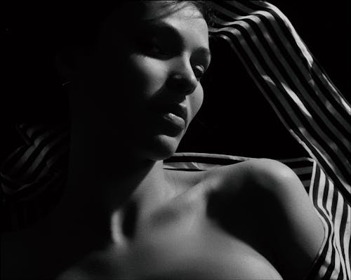 Elegant black and white portrait of a woman with dramatic shadows, conveying a sense of mystery and beauty.