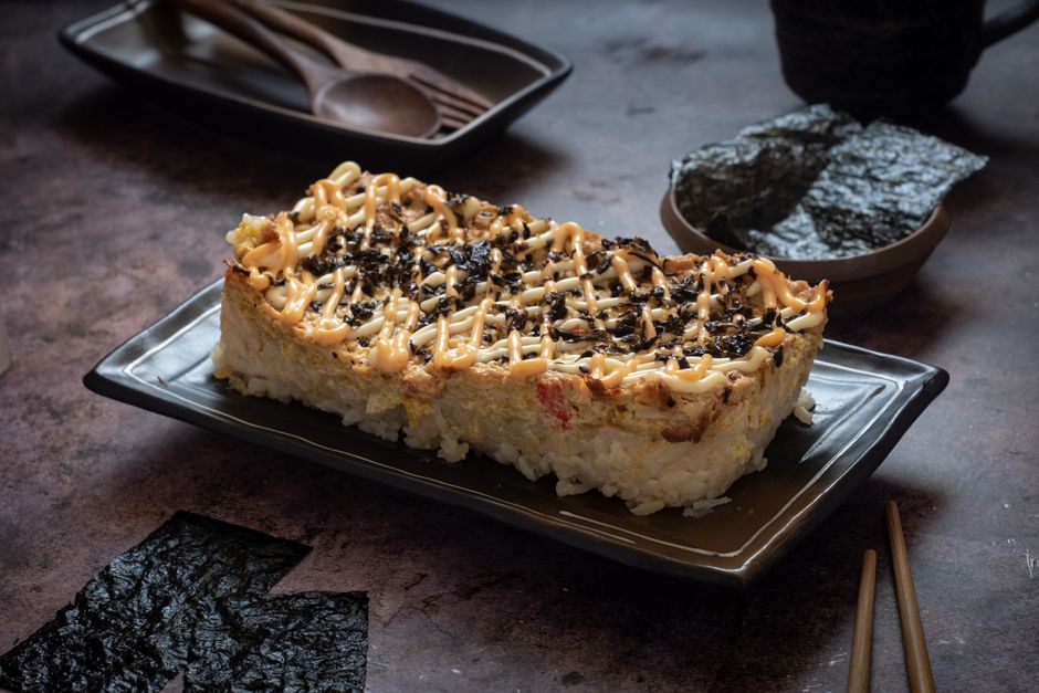 A crowd-size sushi bake with seasoned rice, a creamy baked imitation crab topping, and nori for scooping, all the sushi flavor, none of the rolling.