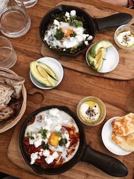 Brunch spread with eggs, avocado, cheese, and toast on a wooden table.