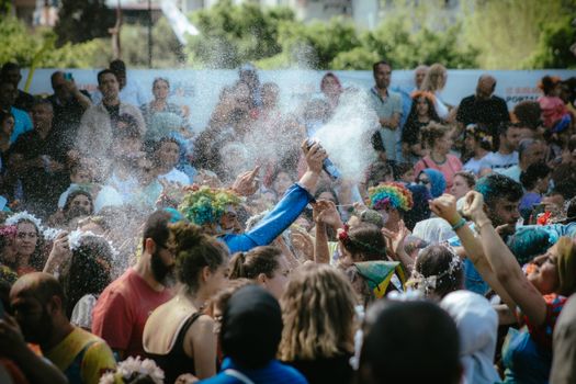 A lively crowd enjoying a colorful outdoor celebration in Adana, Türkiye during the day.