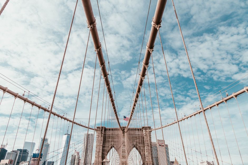 Iconic Brooklyn Bridge showcasing suspension wires with downtown Manhattan skyline.