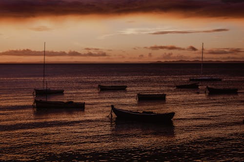 A group of boats in the water at sunset