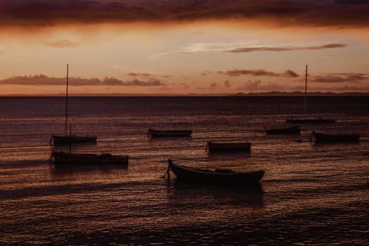 A tranquil scene of boats resting on the sea under a vibrant sunset sky, capturing nature's serene moments.