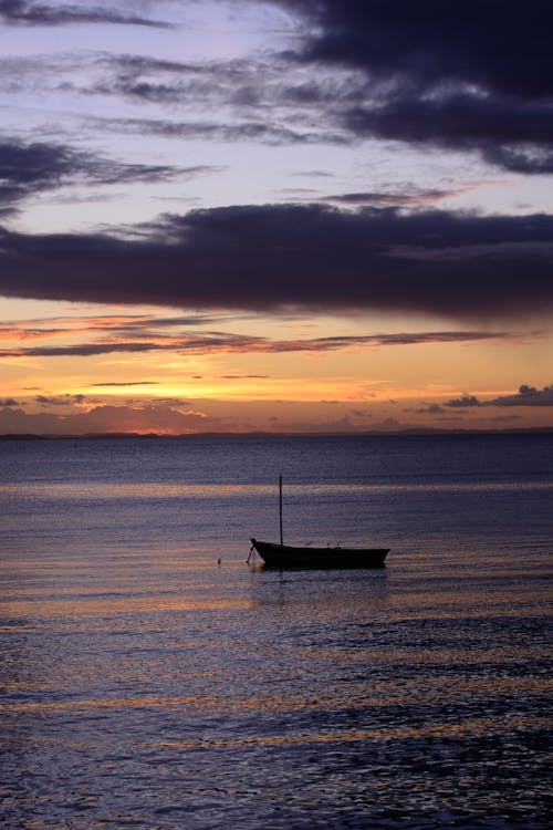 A boat is floating in the ocean at sunset