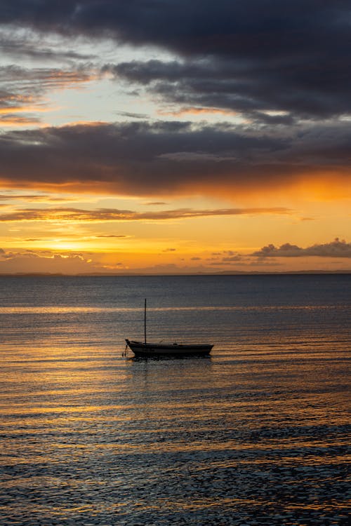 A boat is floating in the ocean at sunset