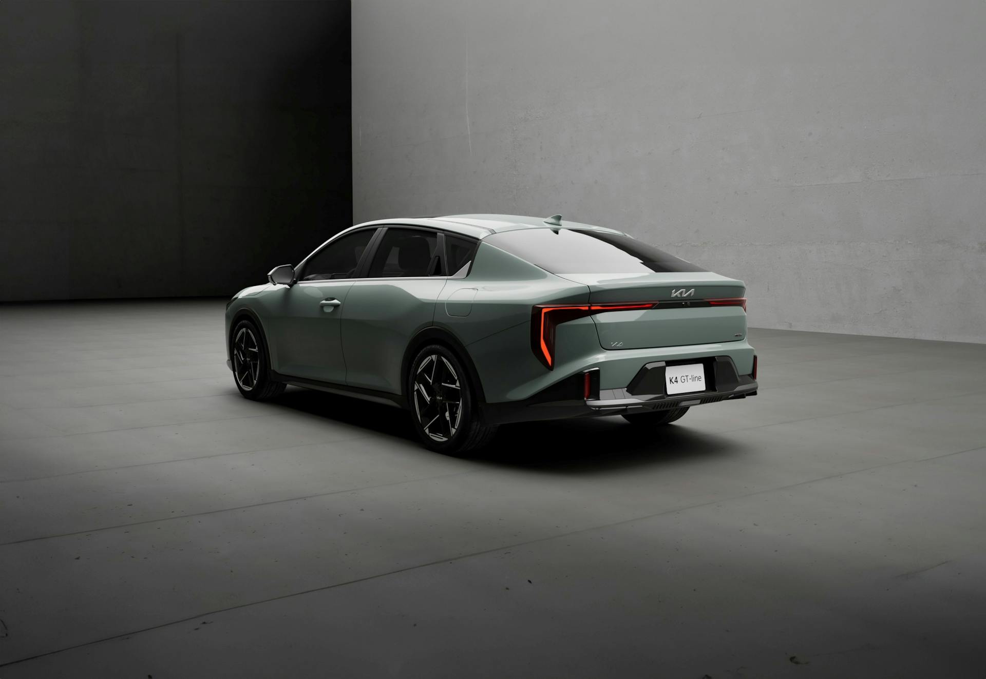 A modern gray Kia K4 GT Line vehicle in a minimalist indoor environment.