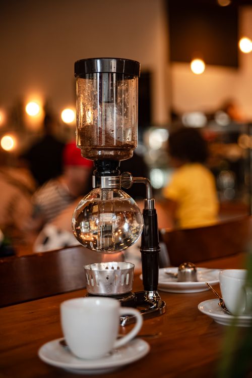 Free Elegant coffee siphon brewing setup on a table in a cozy cafe, capturing a warm ambiance. Stock Photo