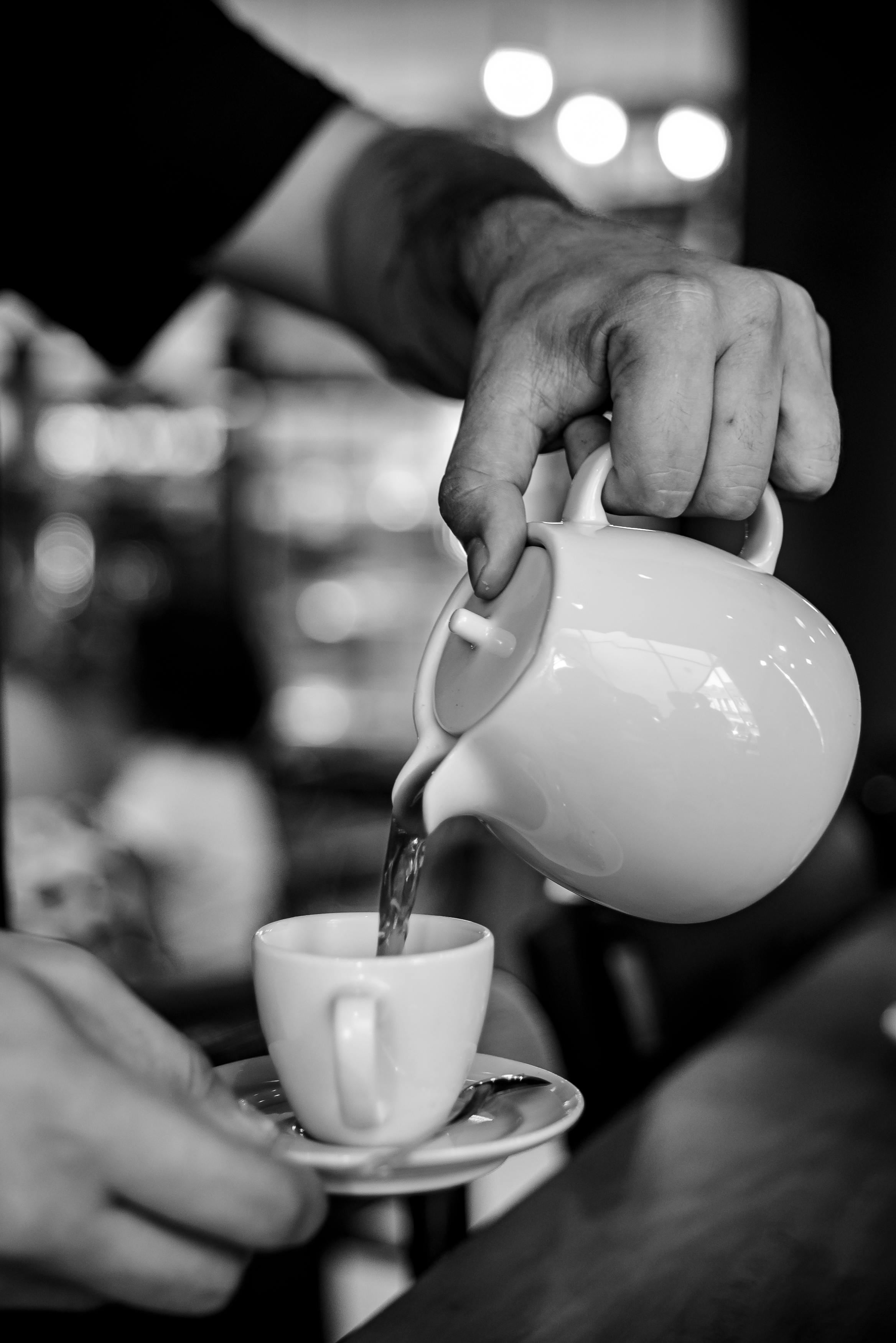 Black and white image of a barista pouring coffee with a jug into a cup in a Rio de Janeiro café.