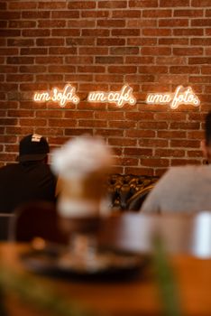 Warm café interior featuring glowing neon sign on a brick wall, perfect for a relaxed ambiance.