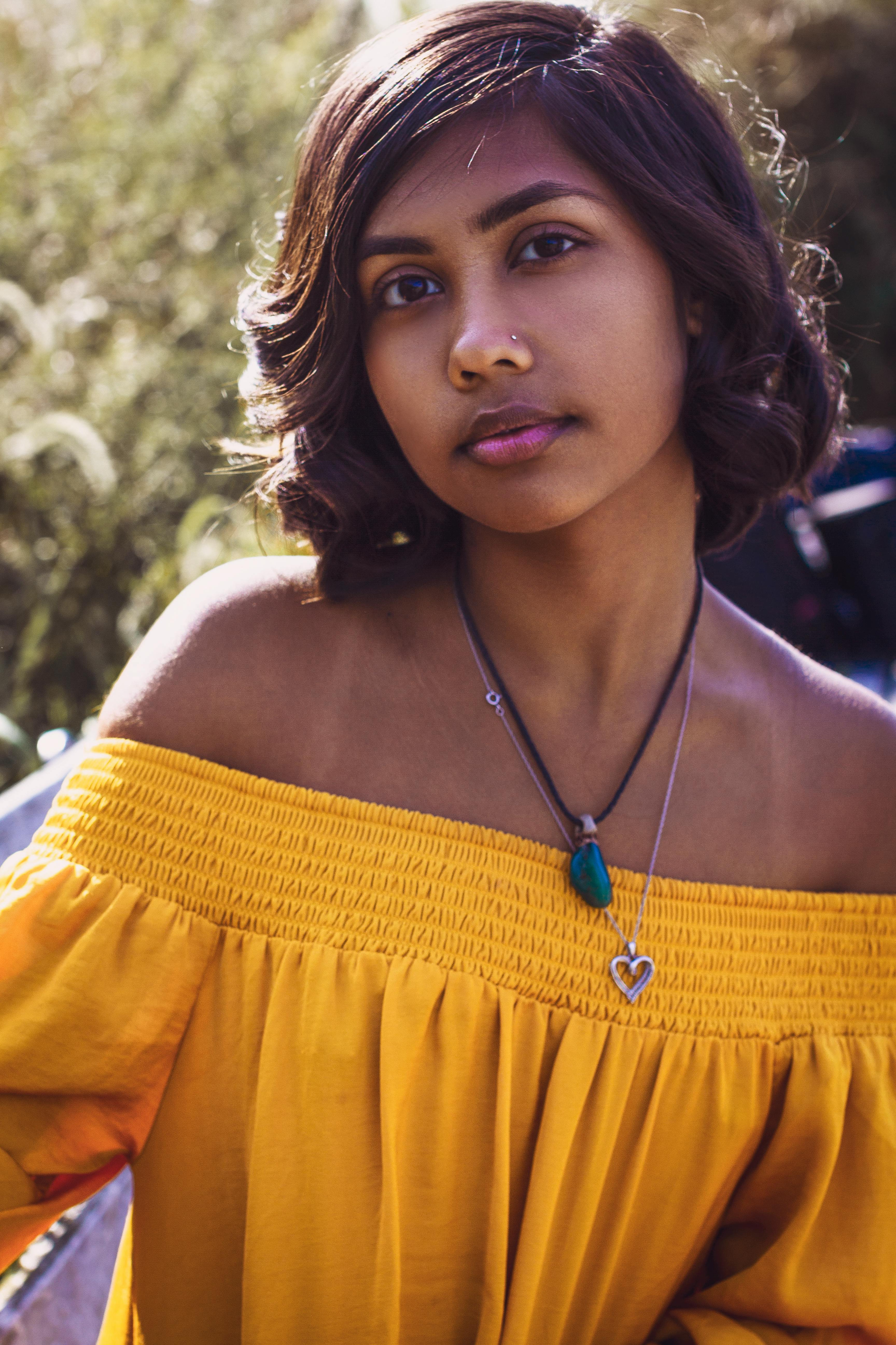 一位身穿黄色露肩连衣裙的短发年轻女子在户外自然光下摆姿势