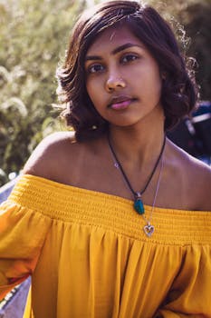 一位身穿黄色露肩连衣裙的短发年轻女子在户外自然光下摆姿势