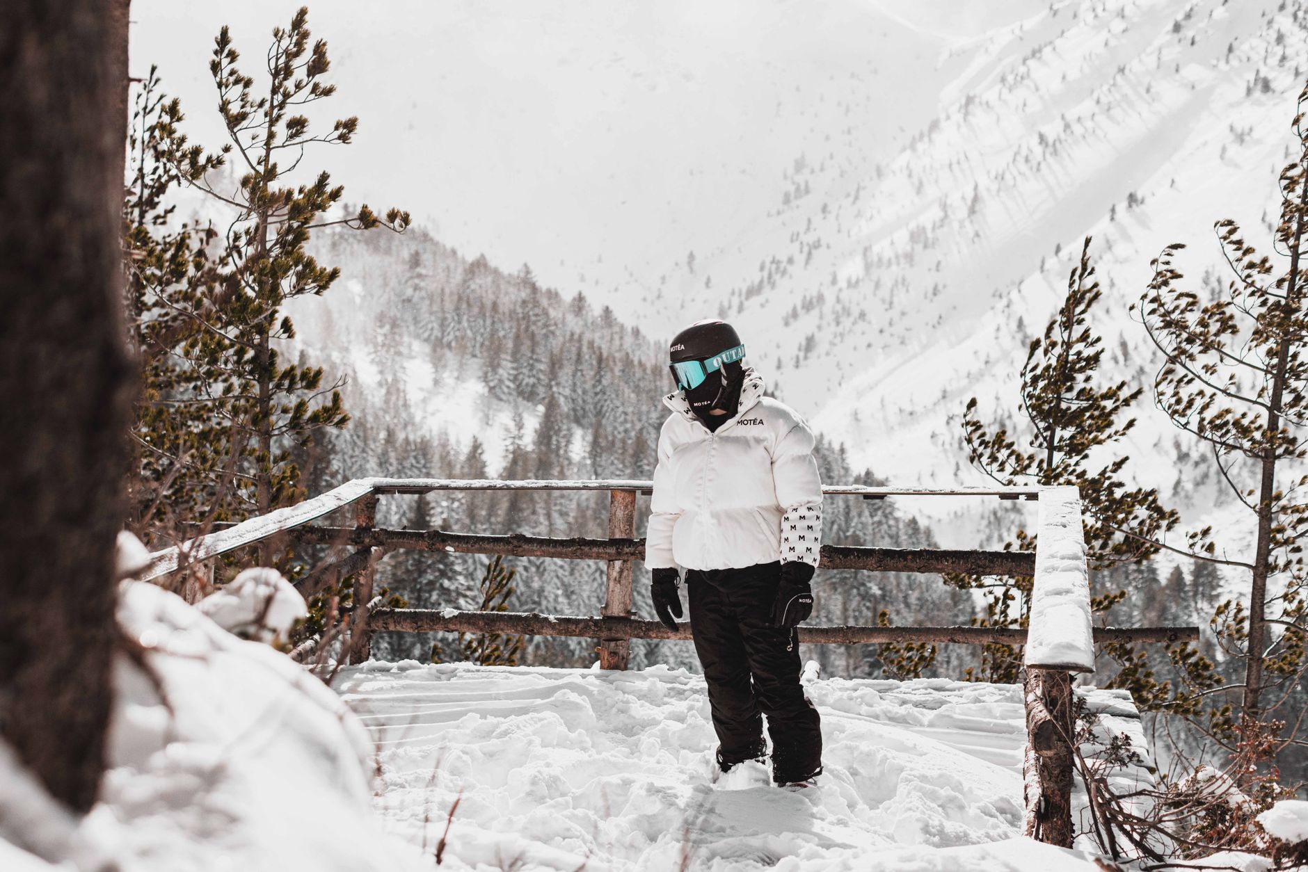 A luxury ski jacket on a wooden ski rack with mountains in the background