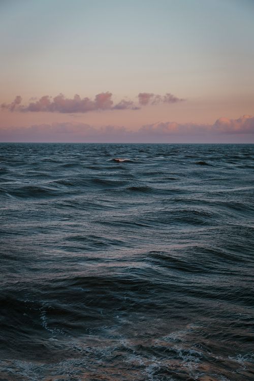 Free Tranquil ocean scene at sunset with gentle waves and colorful sky, perfect for calming visuals. Stock Photo