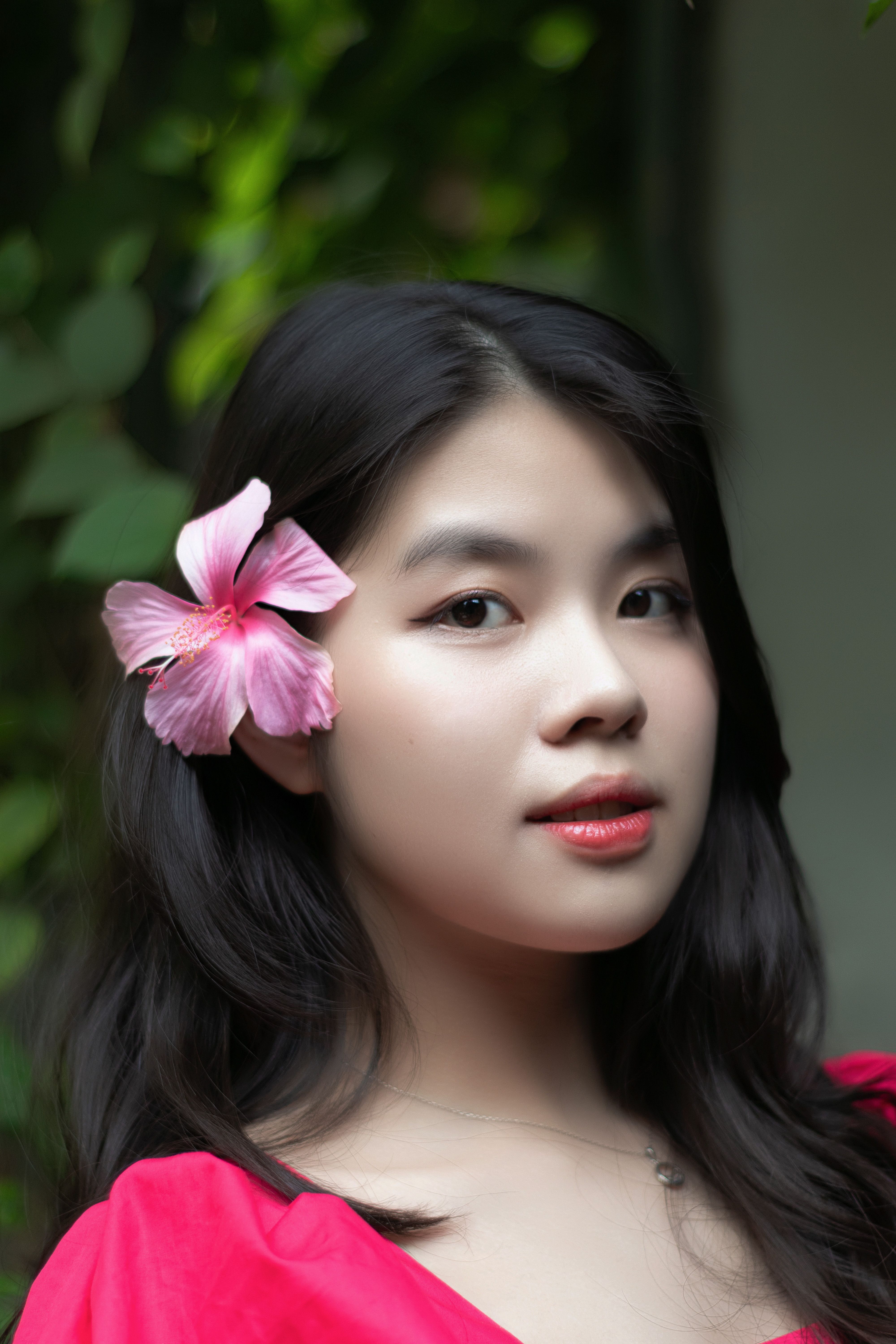 Profile portrait of a woman with a pink flower in her hair, exuding elegance and natural beauty.