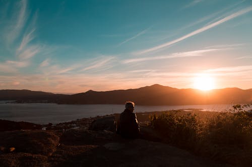 Free Man Sitting Near Body of Water Stock Photo