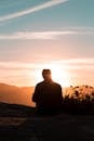 一个人独自坐在山顶上欣赏日落美景