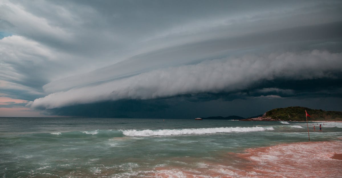 Photo by Arthur Brognoli A dramatic thunderstorm approaches the beach, creating a striking cloudscape over the ocean waves.