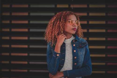 Free Fashionable woman posing in denim jacket and sunglasses with colorful background. Stock Photo